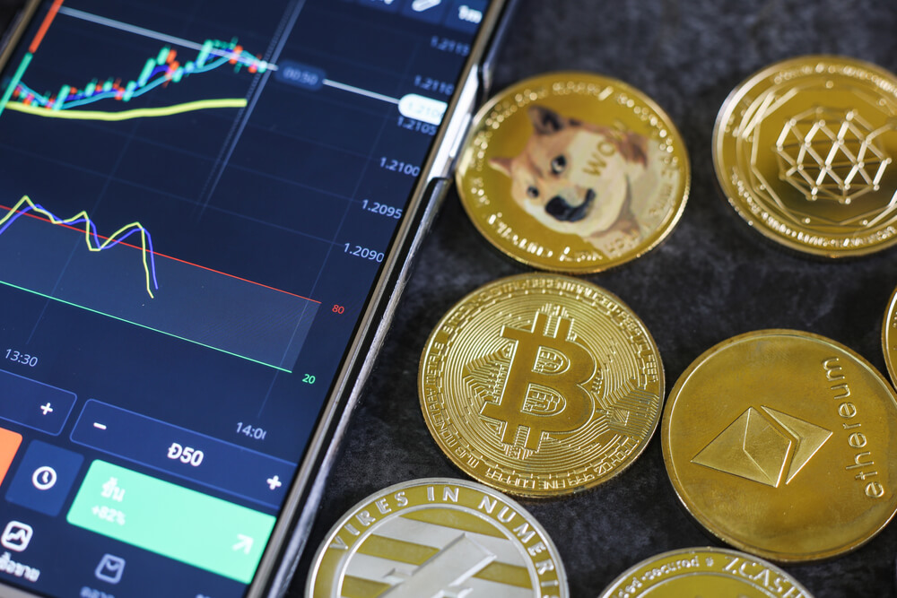 Mobile trading Stocks and Crypto currencies with shiny silver and gold physical digital currency symbols coins.